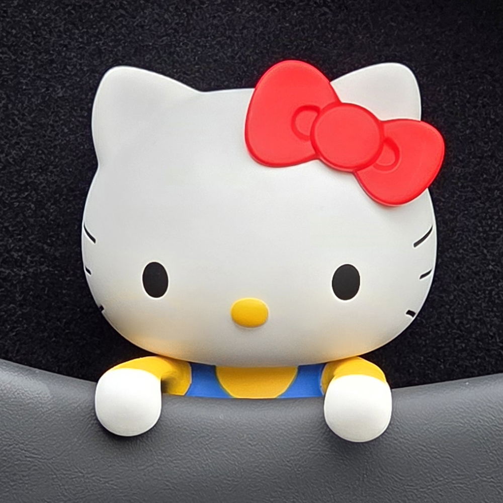 BELLE AMANT Hello Kitty Car Air Freshener peeking over car seat or dashboard edge, blue overalls
