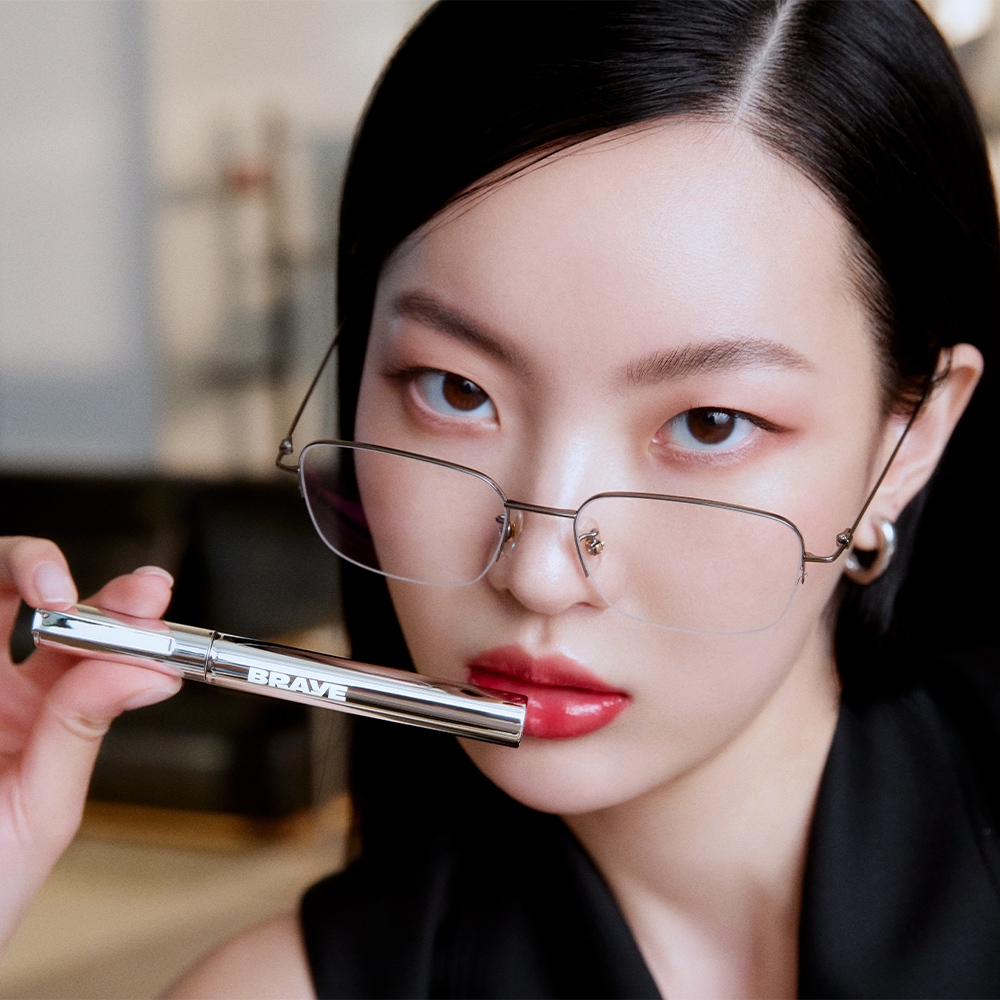 BRAYE Thin Glow Tint silver fountain pen tube held by model, lip tint on lips